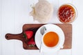 top view of a cup of tea with fresh strawberries on wooden board and strawberry jam in a glass vase on white background Royalty Free Stock Photo