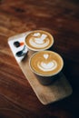 Two cups of cappuccino with latte art on wooden background. Royalty Free Stock Photo