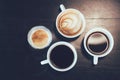 Top view of cups of different flavors hot coffee drink like flat black, cappuccino, latte, and americano on the wooden table