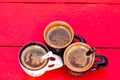 Top view of cups of freshly made coffee on a red wooden surface