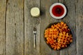 Top view of curd waffles on a plate, apricot jam, a glass of milk and a fork on a wooden table