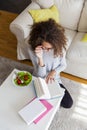 Curly hair teenage girl reading book and eating salad at home Royalty Free Stock Photo