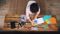 Top view of curly-headed girl creating design from splash-paper displaying figures in notebook then sticking them using