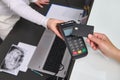 Top view customer hand holds black mockup credit card above a POS terminal, makes cashless payment using NFC technology