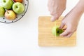 Top view of Cut green apple in half with hands by plastic knife in wooden chopping board. Royalty Free Stock Photo