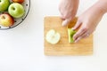 Top view of Cut green apple in half with hands by plastic knife in wooden chopping board. Royalty Free Stock Photo