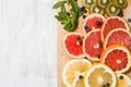 Top view on cut red and yellow grapefruit with mint. Fresh organic citrus, kiwi and blueberry on white wooden background Royalty Free Stock Photo