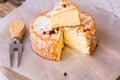 Top view of cut slice of French or German soft cheese with orange rind with mold, creamy texture, red pepper corns, fork