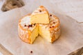 Top view of cut slice of French or German soft cheese with orange rind with mold, creamy texture, red pepper corns