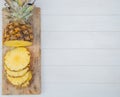 top view of cut and sliced pineapple on cutting board on left side and wooden background with copy space Royalty Free Stock Photo