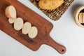 top view of cut and sliced potato on cutting board with whole one in plate and black pepper on white background