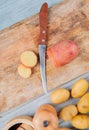 top view of cut and sliced red potato and knife on cutting board with new ones and salt with black pepper seeds on wooden Royalty Free Stock Photo