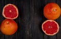 top view of cut and whole grapefruits on left and right sides and black background with copy space