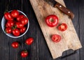 top view of cut and whole tomatoes and knife on cutting board with other ones in bowl on wooden background