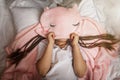 Top view of cute awaking girl with her toy animals wearing in light pink pajama with unicorn hoody Royalty Free Stock Photo