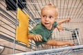 Top view of cute baby sitting in shopping trolley in supermarket and looking at her mom. Mother and little blonde Royalty Free Stock Photo