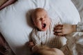 Top view of cute little baby yawning in bed, big sister holding newborn hand. Sisterly love, joy for new family member. Royalty Free Stock Photo