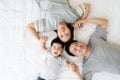 Top view of cute little boy and his asian parents looking at camera and smiling while lying on the white bed at home. Royalty Free Stock Photo