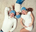 Top view of cute little girl and her beautiful young parents looking at camera and smiling while lying on the floor at Royalty Free Stock Photo