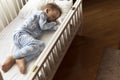 top view Cute little 2-3 years preschool baby boy kid sleeping sweetly in white crib during lunch rest time in blue Royalty Free Stock Photo