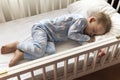 top view Cute little 2-3 years preschool baby boy kid sleeping sweetly in white crib during lunch rest time in blue Royalty Free Stock Photo