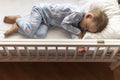 top view Cute little 2-3 years preschool baby boy kid sleeping sweetly in white crib during lunch rest time in blue Royalty Free Stock Photo