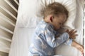 top view Cute little 2-3 years preschool baby boy kid sleeping sweetly in white crib during lunch rest time in blue Royalty Free Stock Photo