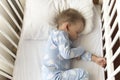 top view Cute little 2-3 years preschool baby boy kid sleeping sweetly in white crib during lunch rest time in blue Royalty Free Stock Photo