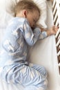 top view Cute little 2-3 years preschool baby boy kid sleeping sweetly in white crib during lunch rest time in blue Royalty Free Stock Photo