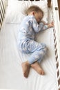 top view Cute little 2-3 years preschool baby boy kid sleeping sweetly in white crib during lunch rest time in blue Royalty Free Stock Photo