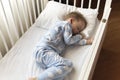 Top view Cute little 2-3 years preschool baby boy kid sleeping sweetly in white crib during lunch rest time in blue pajama with Royalty Free Stock Photo