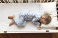 top view Cute little 2-3 years preschool baby boy kid sleeping sweetly in white crib during lunch rest time in blue Royalty Free Stock Photo