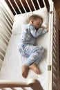 top view Cute little 2-3 years preschool baby boy kid sleeping sweetly in white crib during lunch rest time in blue Royalty Free Stock Photo