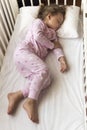 top view Cute little 3-4 years preschool baby girl kid sleeping sweetly in white crib during lunch rest time in pink Royalty Free Stock Photo