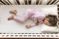 Top view Cute little 3-4 years preschool baby girl kid sleeping sweetly in white crib during lunch rest time in pink pajama with Royalty Free Stock Photo