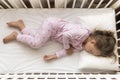 top view Cute little 3-4 years preschool baby girl kid sleeping sweetly in white crib during lunch rest time in pink Royalty Free Stock Photo