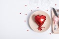 Top view cutlery and plate with red heart-shaped balloon on the table. Serving for romantic dinner on valentines day