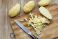 Top view of cutted scrubbed boiled potatoes in jackets using knife on the wooden background