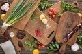 Top view of cutting boards, cherry tomatoes, salt, garlics, cucumbers, chili peppers, pepper mill, meat chopper, lemons