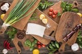 Top view of cutting boards, cherry tomatoes, salt, garlics, cucumbers, chili peppers, pepper mill, meat chopper, lemons