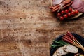 Top view of cutting boards with olives in bowls, delicious smoked sausages, salami, bread, tomatoes and herbs on wooden table Royalty Free Stock Photo