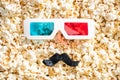 top view of 3d glasses and artificial mustache on scattered popcorn, cinema concept.