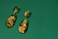 Top view of dangle earrings made of epoxy resin with golden foil inside isolated over green background