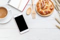 Top view danish pastries, coffee, note book and smartphone on white wooden table