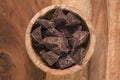 Top view dark chocolate chunks in wood bowl on table