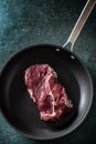 Top view of a dark pan with a raw chunk of steak meat on a marble surface Royalty Free Stock Photo