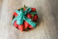 Top view of delicious big red strawberry in round wooden plate tired up  by measuring tape Royalty Free Stock Photo