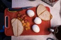 Top view of a delicious breakfast with eggs, cherry tomatoes and bread slices on a red food board Royalty Free Stock Photo