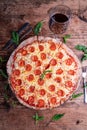 Top view of a delicious cheesy pepperoni pizza with a glass of wine on a wooden table Royalty Free Stock Photo