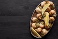 Top view of delicious cooked escargots with lemon on black wooden table.